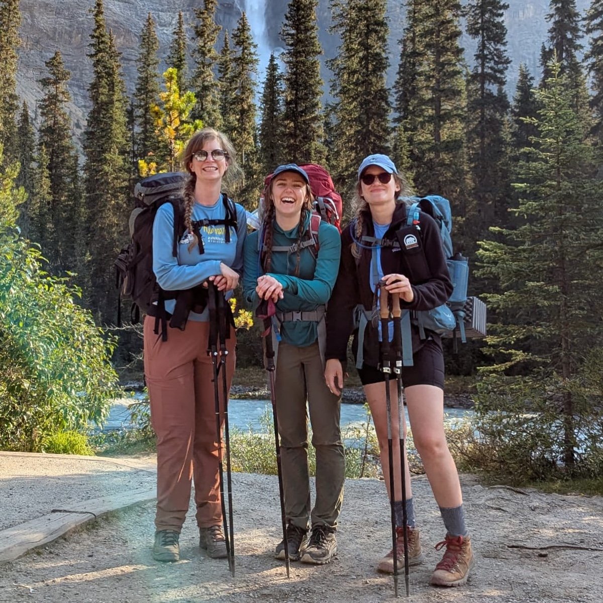 Three hikers pictured in front of a waterfall and river