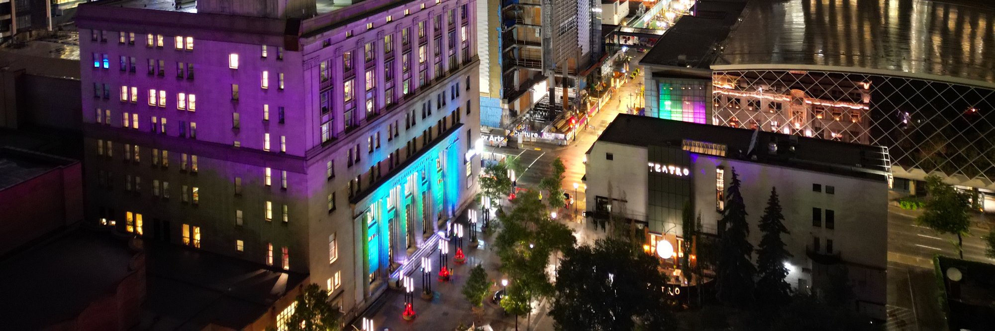 Stephan looking west from Olympic Plaza, the Jack Singer Concert Hall facade is lit up in blues and purple.